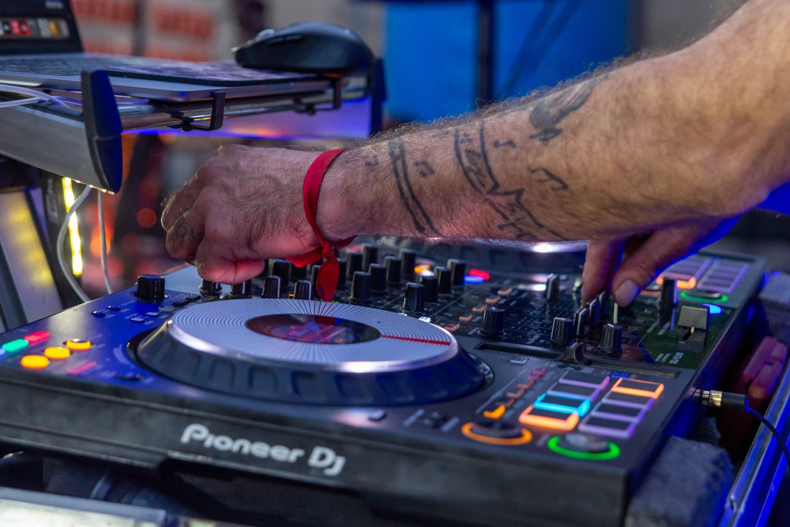 Close-up of hands mixing on a DJ controller under party lighting